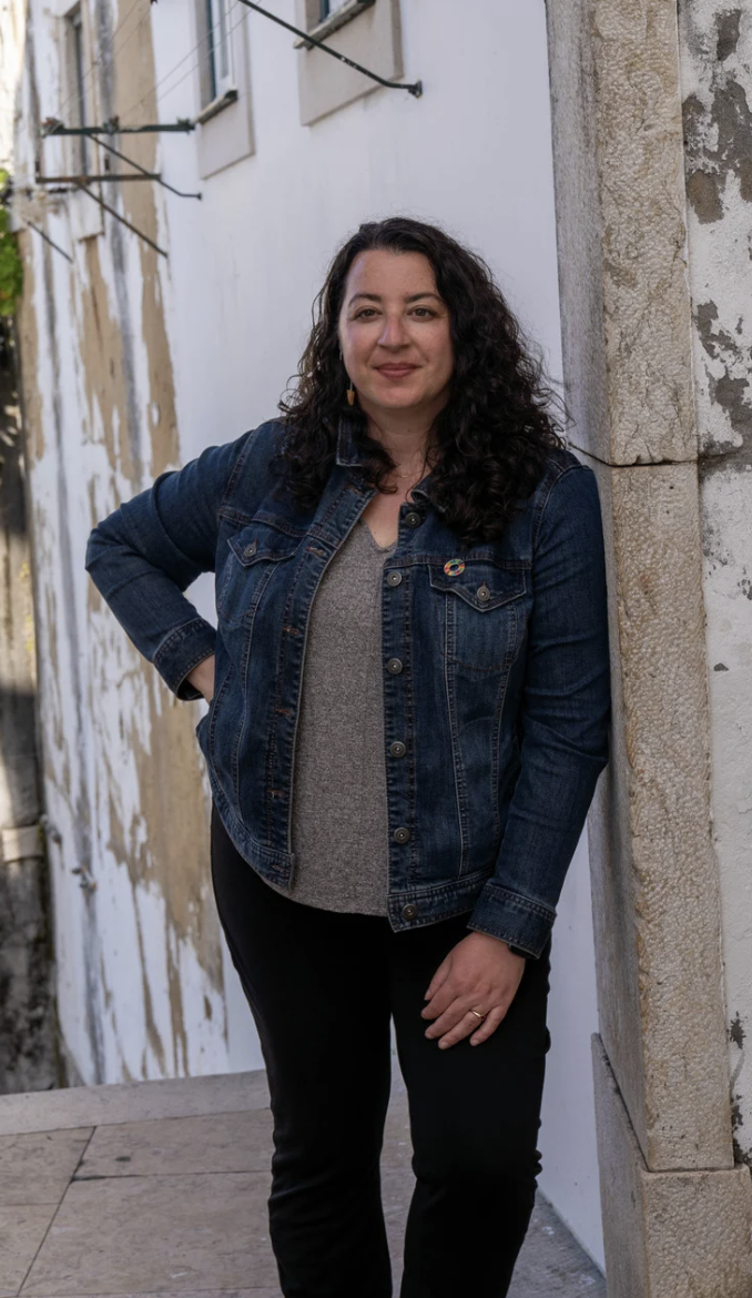 A woman leaning against an outdoor archway.